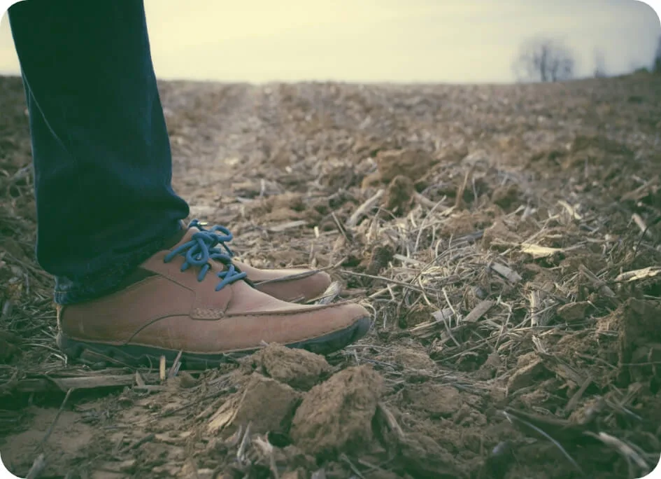 A farmer walking across dry agricultural soil